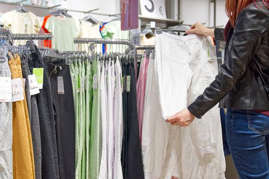 Shopper woman choosing clothes thinking looking at clothing while shopping in store. shopaholic woman chooses clothes in the store