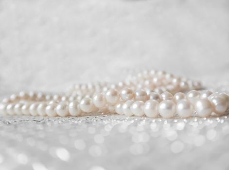 Nature white string of pearls on a sparkling background in soft focus, with highlights