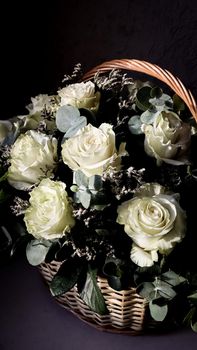 Bouquet of beautiful white roses in a wicker basket on a dark background. Perfect for greeting card