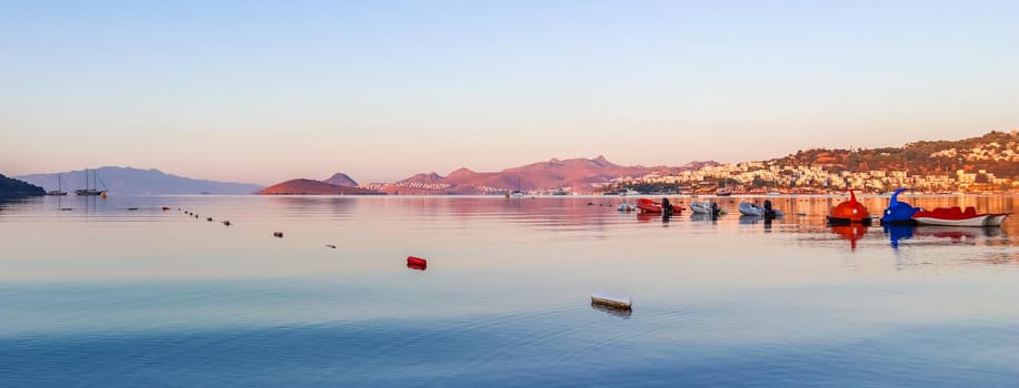 Beautiful sunrise on Mediterranean coast with islands and mountains, boats and catamarans