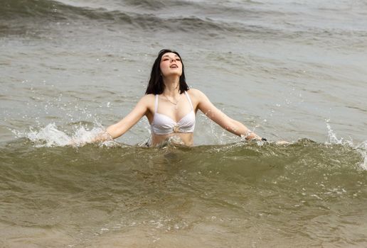 young brunette woman swiming in the sea on sunny summer day