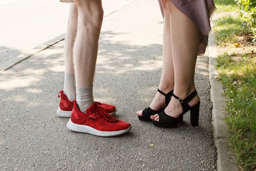 legs of a man and a woman facing each other. standing on sidewalk on summer day