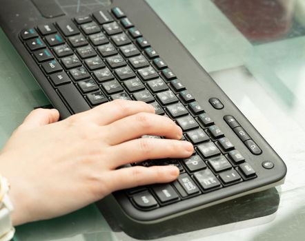 woman hand on wireless blutooth key board on glass top table with copy space