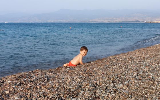 Healthy lifestyle. Little boy resting and having fun on a rocky beach on the Mediterranean coast