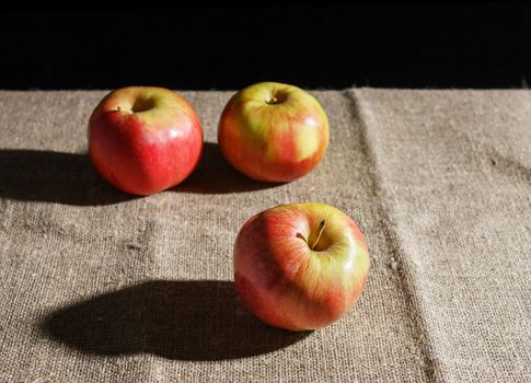 three red apples on the table. closeup on black background