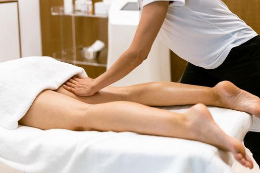 Middle-aged woman having a leg massage in a beauty salon. Body care treatment in a beauty centre.