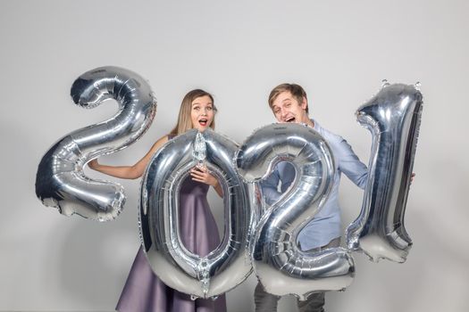 Party, people and new year holidays concept - woman and man celebrating new years eve 2021.