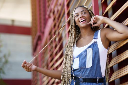 Happy young black woman with coloured braids. Typical African hairstyle.