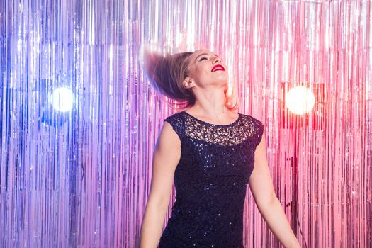 Young blonde woman dancing at night disco club