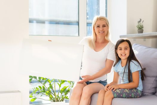 mother and daughter hangs a large photo canvas at home