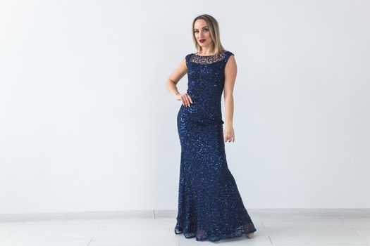 Fashionable young woman in beautiful dress posing at studio. Isolated over white.