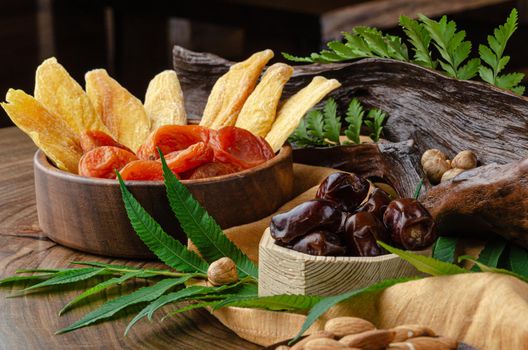 still life of nuts and dried fruits on a wooden table with fern leaves