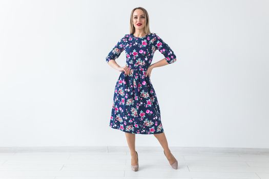 Fashionable young woman in beautiful dress posing at studio. Isolated over white.