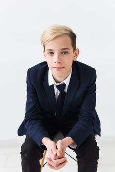 Portrait of stylish school boy teenager in white shirt and jacket against white background with copy space