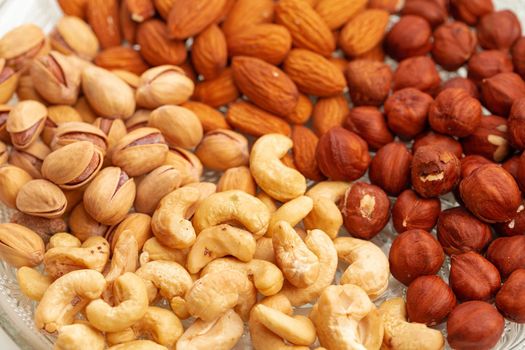 Assortment of dry nuts on glass plate, close up photo