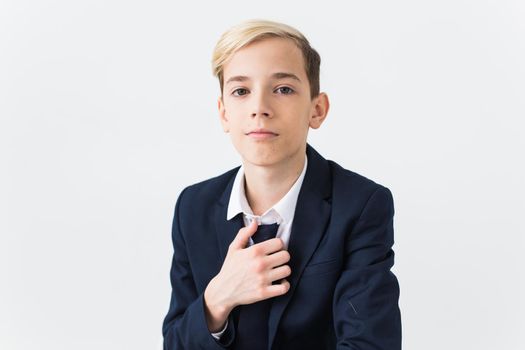 Portrait of stylish school boy teenager in white shirt and jacket against white background with copy space