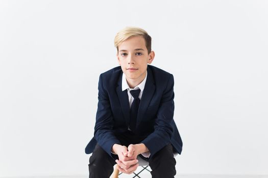 Portrait of stylish school boy teenager in white shirt and jacket against white background with copy space