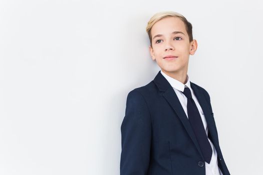 Portrait of stylish school boy teenager in white shirt and jacket against white background with copy space