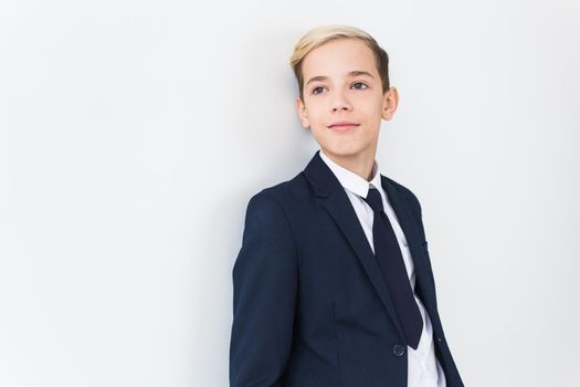 Portrait of stylish school boy teenager in white shirt and jacket against white background with copy space