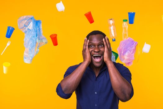 World Environment Day, plastic recycling problem and environmental disaster concept - Terrified man on yellow background with trash.