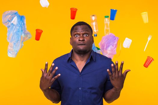 World Environment Day, plastic recycling problem and environmental disaster concept - Terrified man on yellow background with trash.