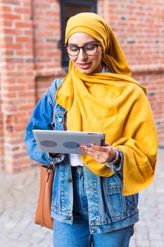 Arab woman student. Beautiful muslim female student wearing yellow hijab holding tablet