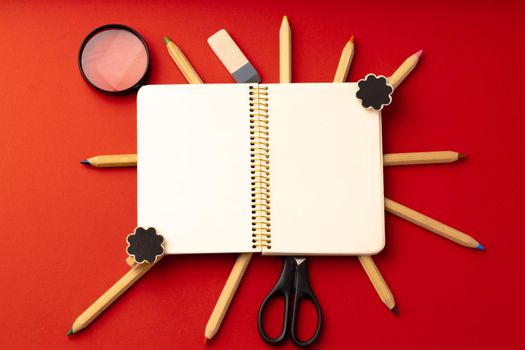 Open notepad and color pencils on paper background top view