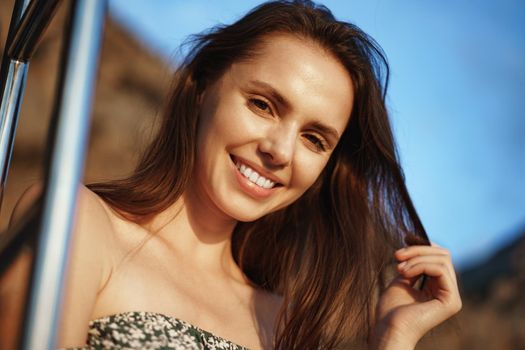 Young pretty woman in floral dress posing on yacht in the sea