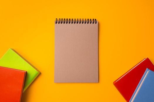Hardcover notepads on yellow background top view, copy space