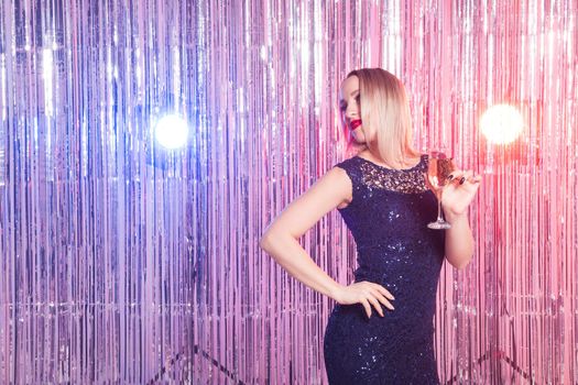 drinks, holidays and celebration concept - smiling woman in evening dress with glass of sparkling wine over shiny background