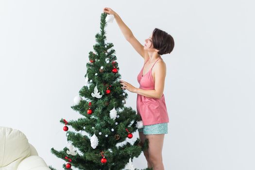 Beautiful young woman decorating a Christmas tree. Holidays and celebrations.