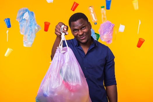 Problem of trash, plastic recycling, pollution and environmental concept - man carrying garbage bag on yellow background.