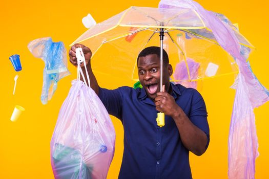 Plastic recycling problem, ecology and environmental disaster concept - Scared man screaming on yellow background with trash. He is worried about ecology disaster.
