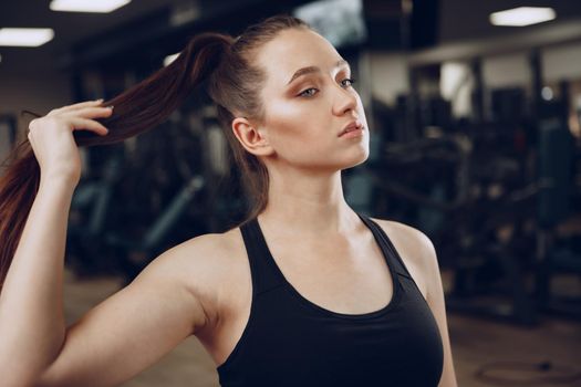 Brunette young woman sitting tired in a gym after workout close up