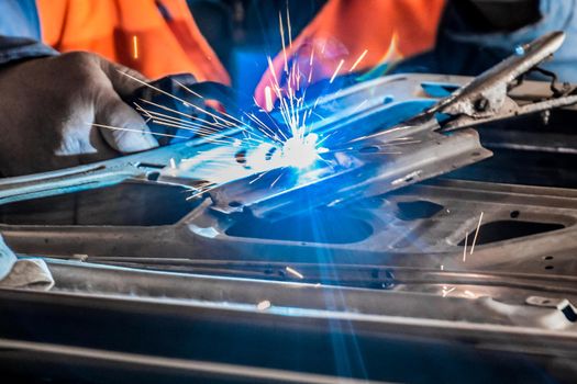 Close-up of the process of welding and repair of the car door. Industrial works.