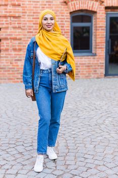 Arab woman student. Beautiful muslim female student wearing yellow hijab holding tablet