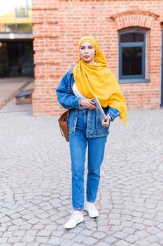 Arab woman student. Beautiful muslim female student wearing yellow hijab holding tablet