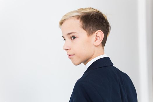 Portrait of stylish school boy teenager in white shirt and jacket against white background with copy space