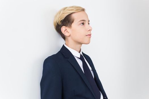 Portrait of stylish school boy teenager in white shirt and jacket against white background with copy space