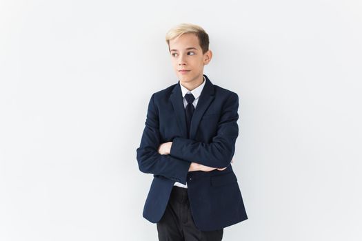 Portrait of stylish school boy teenager in white shirt and jacket against white background with copy space