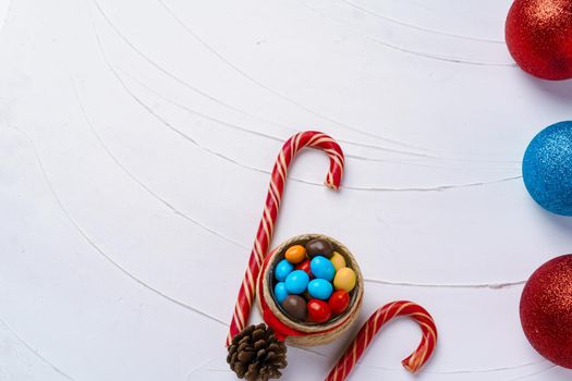 Festive background with candy canes and Christmas baubles on wooden board