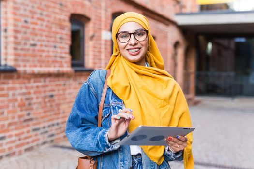 Arab woman student. Beautiful muslim female student wearing yellow hijab holding tablet