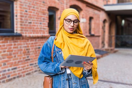 Arab woman student. Beautiful muslim female student wearing yellow hijab holding tablet