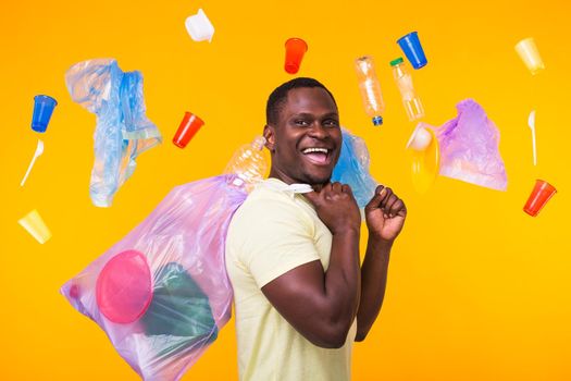 Problem of trash, plastic recycling, pollution and environmental concept - confused man carrying garbage bag on yellow background.