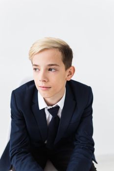 Portrait of stylish school boy teenager in white shirt and jacket against white background with copy space