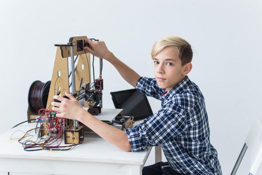 Education, children, technology concept - teen boy is printing on 3d printer