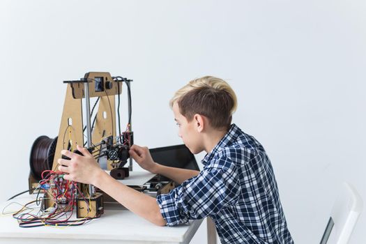 Education, children, technology concept - teen boy is printing on 3d printer