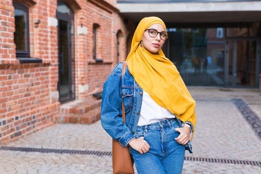 Beautiful Arabic muslim woman wearing yellow hijab, stylish female face portrait over city street
