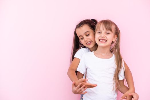 Two little girls - best friends, isolated over on a pink background