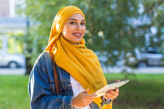 Arab woman student. Beautiful muslim female student wearing yellow hijab holding tablet